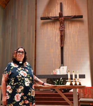 Rev. Miranda Hasset stands before the altar of the St. Dunstan's Episcopal Church she has been rector for 11 years and is on a mission to learn more about the history of the land obtained during the Blackhawk War. This war displaced and massacred local natives which the church has now sought to acknowledge through a Land Acknowledgment Task Force which began work in the summer of 2021. The church incorporates a natural wood interior and exterior that integrates the vast forestry of the land it sits on. (Amena Saleh / Wisconsin Watch)