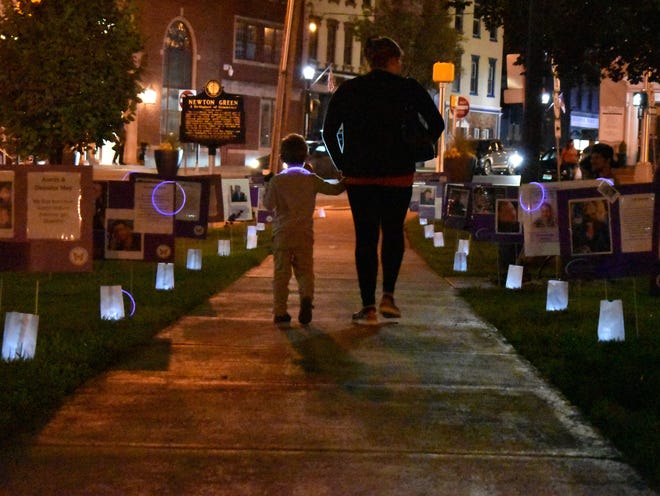 Luminaries and photos of local residents lost to drug overdose line pathways on the Newton Green during a vigil marking International Overdose Awareness Day Wednesday, Aug. 31, 2022.