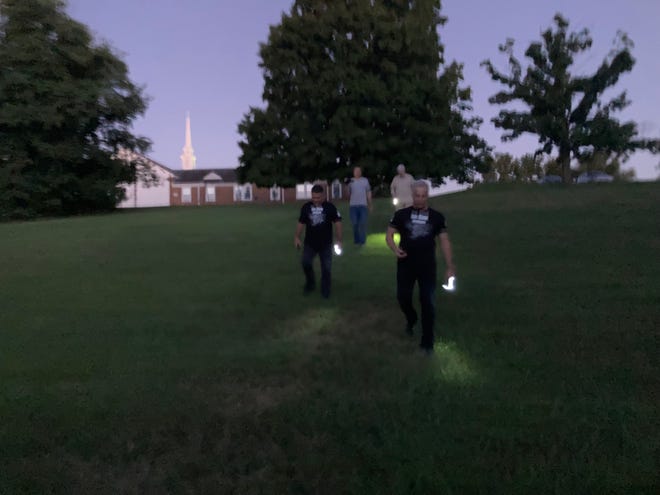 Eric Mintel (front, right) leads his team of paranormal investigators down a hill toward a field and woods where Rich Show said he encountered the 