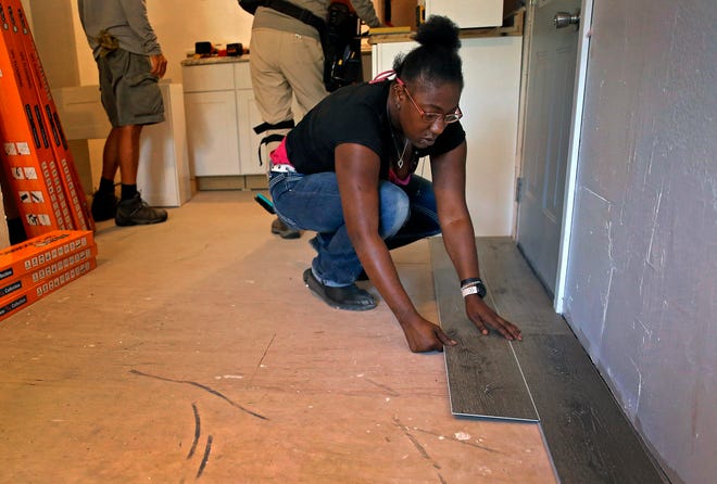 Homeowner Anastasia Hillard lays down flooring Aug.  27, 2022, inside her home in Oklahoma City.  Volunteers and workers with Central Oklahoma Habitat for Humanity's Critical Home Repair Program worked over several weekends making major repairs to Hillard's home.