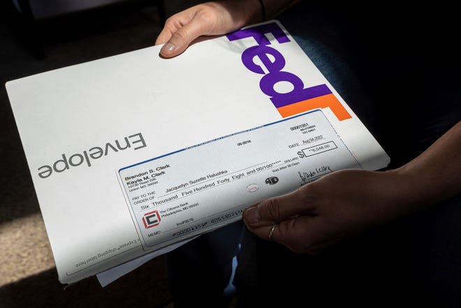 Jacquelyn Halushka, 27, sits inside her home as she holds a check for $6,548 on Aug. 23, 2022. The check was meant to be deposited to Halushka for