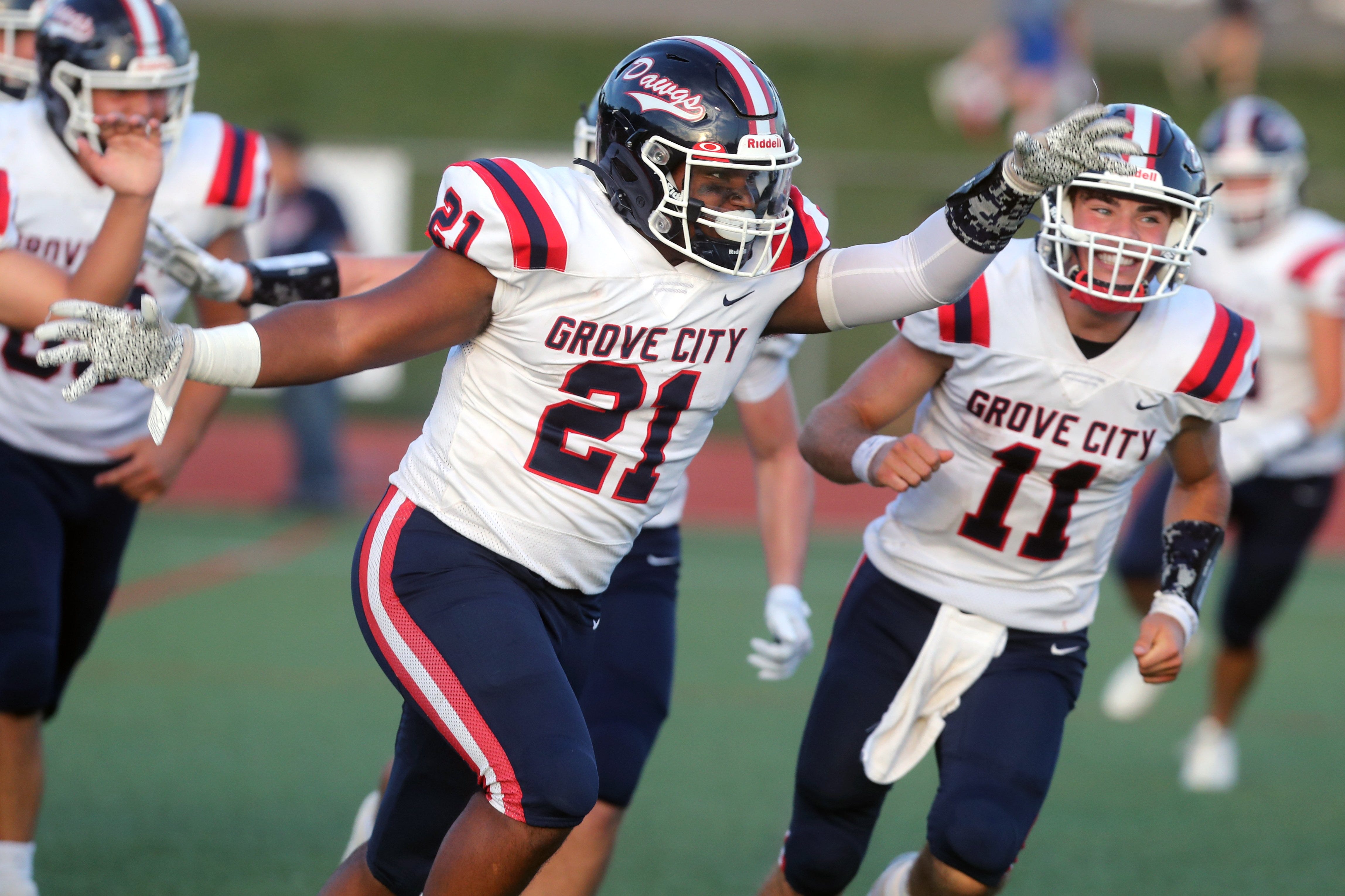 Grove City's Jaeson Thrweatt (21) celebrates with Matthew Papas (11) and other teammates after a 15-yard touchdown run during a game against Thomas Worthington on Sept. 2 at Thomas Worthington High School.
