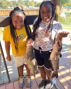 Malayshia Favors, 8, left, and Amaya Favors , 9, teamed up to bag these two hefty channel catfish during the Catfish Derby at Oak Grove Park on August 27. Malayshia won first place in the 8 and under diversion, while Amaya placed first in the and 9 to 12 age division.
