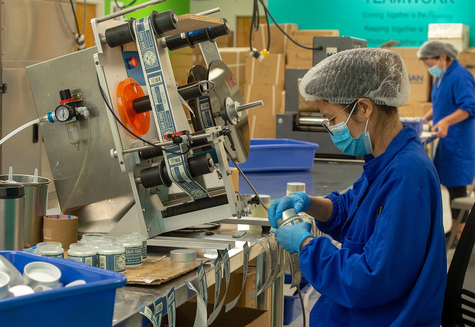 Adhering labels to jars of skin cream by an employee at Fairy Gene in Bristol, a manufacturing company of cosmetics and skincare products, Tuesday, Sept. 6, 2022.