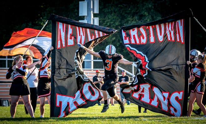 Newcomerstown's Hunter Amore bursts through the banner welcoming the team to the field at Lee Stadium on August 26.  The Newcomerstown community celebrated the 100th anniversary of local school football with a gathering of former players, coaches, cheerleaders and more.