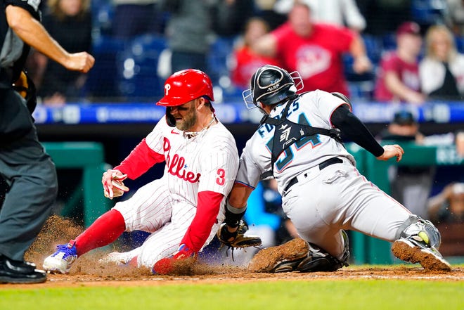 Philadelphia Phillies' Bryce Harper, left, scores the game-winning run past Miami Marlins catcher Nick Fortes on an RBI-single by Jean Segura during the ninth inning of a baseball game, Tuesday, Sept. 6, 2022, in Philadelphia. (AP Photo/Matt Slocum)