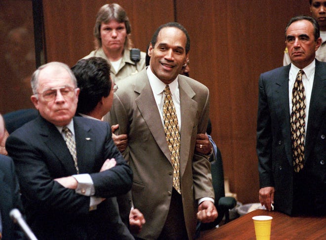 In this Oct. 3, 1995, file photo, O.J. Simpson, center, clenches his fists in victory after the jury said he was not guilty in the murders of his ex-wife Nicole Brown Simpson and her friend Ronald Goldman in a Los Angeles courtroom as attorneys F. Lee Bailey, left, and Robert Shapiro, right, look on. 