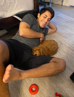 Robert Garon, 23, plays with his puppy, Buzz Lightyear, a 5-month-old Goldendoodle who died July 29 due to possible head trauma.