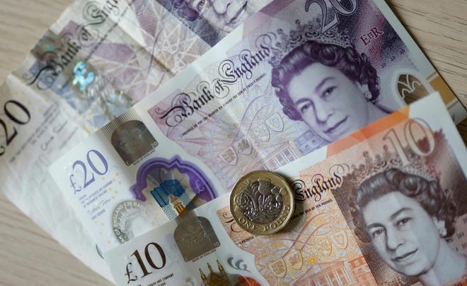 A file photo taken on April 22, 2022 shows British pound coins and banknotes displayed on a table in London. Paper money will eventually change after the death of Queen Elizabeth II.
