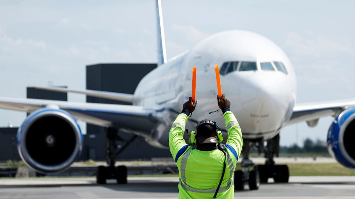 A United Airlines worker guides a plane at Dulles International Airport on June 17, 2022.