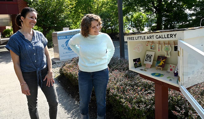 Anna Ryan, left, and Bethany Shaw of Sudbury with the Free Little Art Gallery that they created in front of the Goodnow Library in Sudbury. Visitors can take and/or contribute pieces to the gallery.