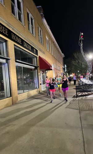Runners head down a Shelby city street early Friday morning. The run was organized as a way to bring attention to safety for women and pay tribute to Eliza Fletcher, a Tennessee woman who was abducted and killed last week.