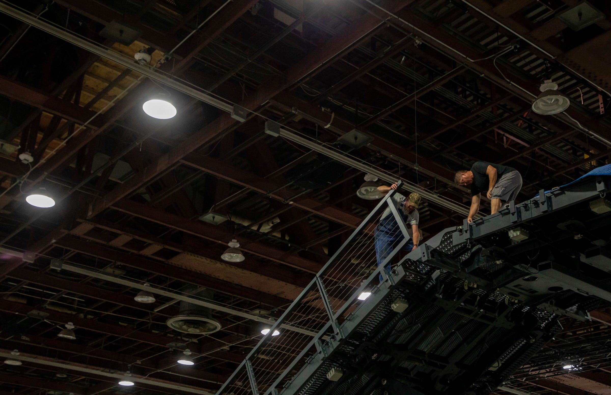 Two employees work on the Ford Motor Co. metal ramp to prepare for the North American International Auto Show inside the Huntington Place convention center in Detroit on Wednesday, Sept. 7, 2022.