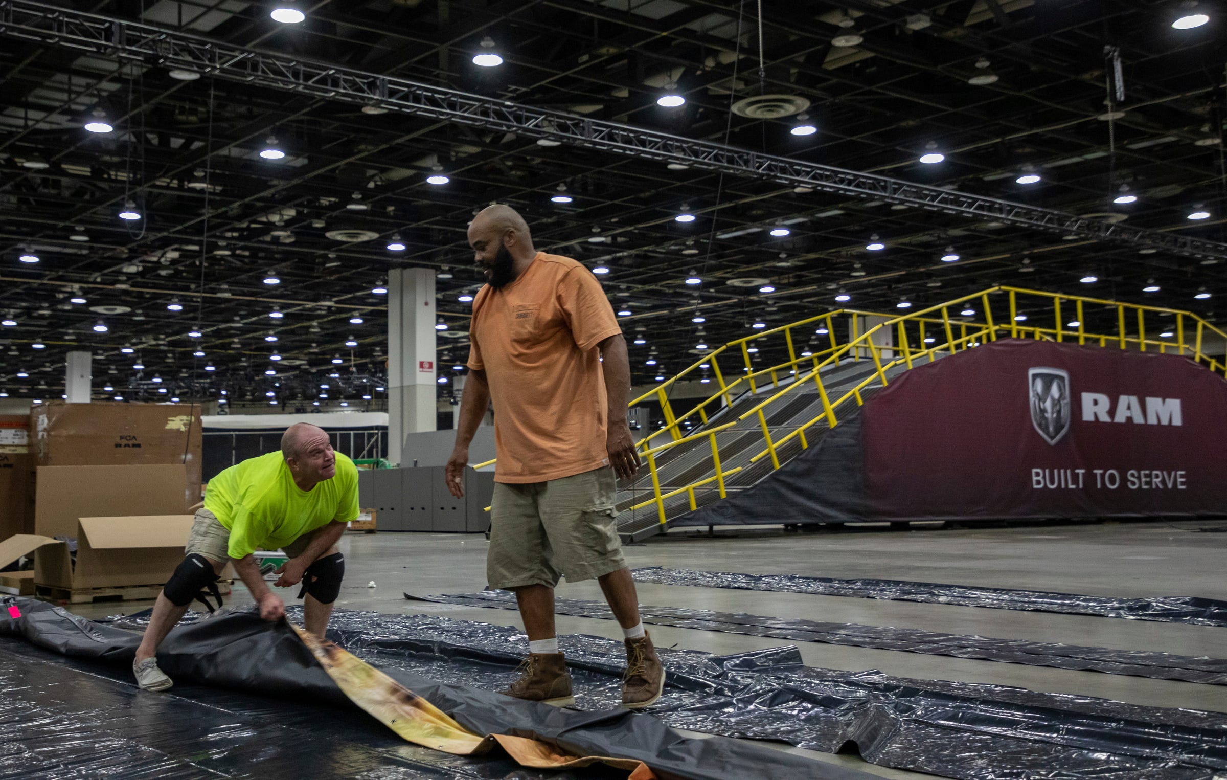 Local union workers Steve Clifford, 56, left, and Robert Embryo roll a large Jeep display before the 2022 North American International Auto Show inside the Huntington Place convention center in Detroit on Friday, Sept. 2, 2022.