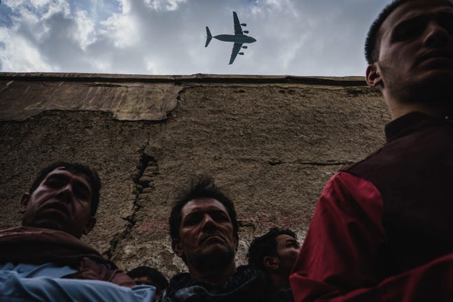 A military transport plane flies over relatives and neighbors of the Ahmadi family in Kabul on Aug. 30, 2021.