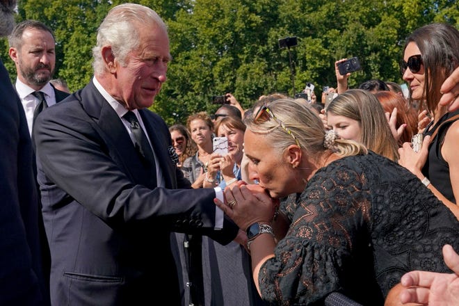 Seorang simpatisan mencium tangan Raja Inggris Charles III saat dia berjalan di luar di Istana Buckingham setelah kematian Ratu Elizabeth II pada hari Kamis, di London, Jumat, 9 September 2022.