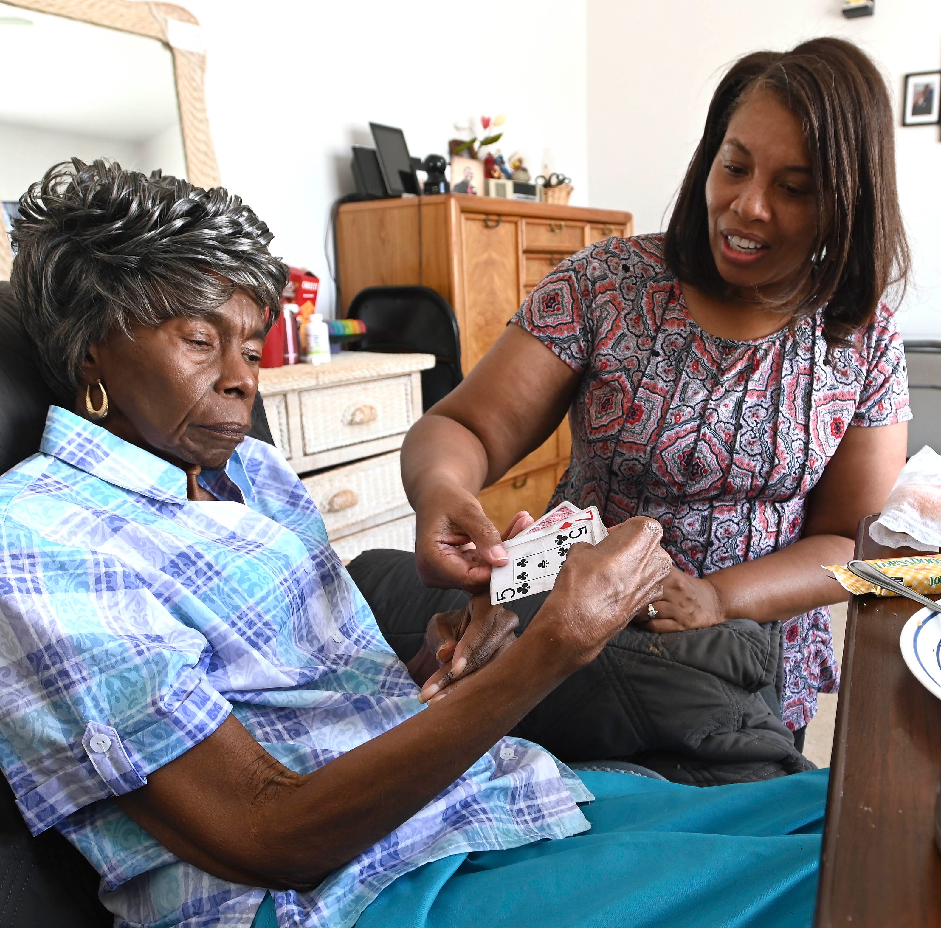 Doria Rainey, right, hands her mother, Mariea Claxton, a deck of cards for later. Rainey is her mother's full-time caregiver as Claxton suffers from dementia.