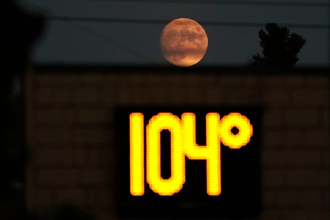 A temperature of 104 degrees is displayed on a digital thermometer as the moon rises over Sacramento, Calif., Thursday, Sept. 8, 2022. A heat wave setting several high-temperature marks in California.
