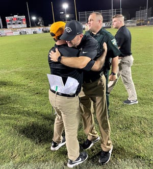 Milton head coach Kelly Gillis (black hat) hugs one of his assistant coaches after the Panthers defeated Booker T. Washington 47-31 on Saturday, Sept. 10, 2022 from Haywood Hanna Stadium.