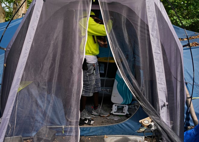 Tim Marshall removes lights hanging inside his tent in Camp Shameless earlier this month as he and many remaining residents of the homeless camp on Columbus' Near East Side prepared to move into temporary, transitional housing as part of a pilot program by the city of Columbus.