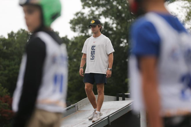 Olimpietis Zeks DiGregorio no Midvejas skatās, kā dalībnieks dodas trasē, pētot ASV kamaniņu sporta komandas slīdni Džona Makgoverna pamatskolā Midvejā 2022. gada 11. septembrī.