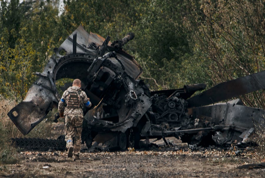 A Ukrainian soldier passes by a Russian tank damaged in a just freed territory in the Kharkiv region on Sept. 11, 2022.