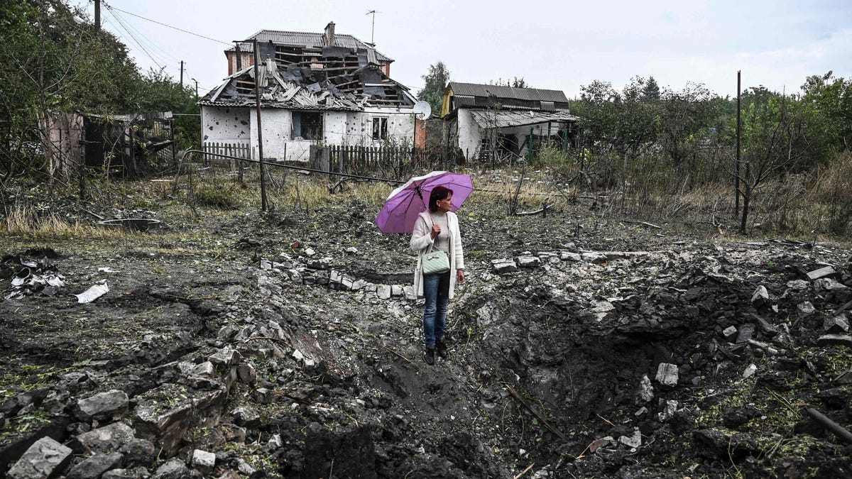 A woman stands in front of a destroyed house, in Kramatorsk, Donetsk region, on September 12, 2022, amid the Russian invasion of Ukraine.