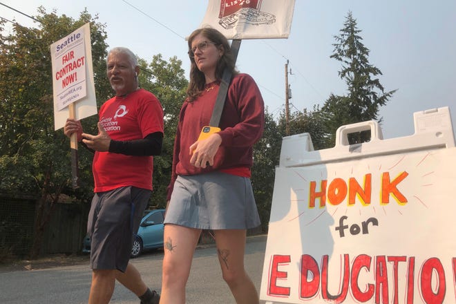 Guillermo Carvajal, a member of the support staff at Northgate Elementary School in Seattle, and Erin Carroll, an occupational therapist there, picket outside the building on the third day of a strike by the Seattle Education Association on Friday, Sept. 9, 2022.