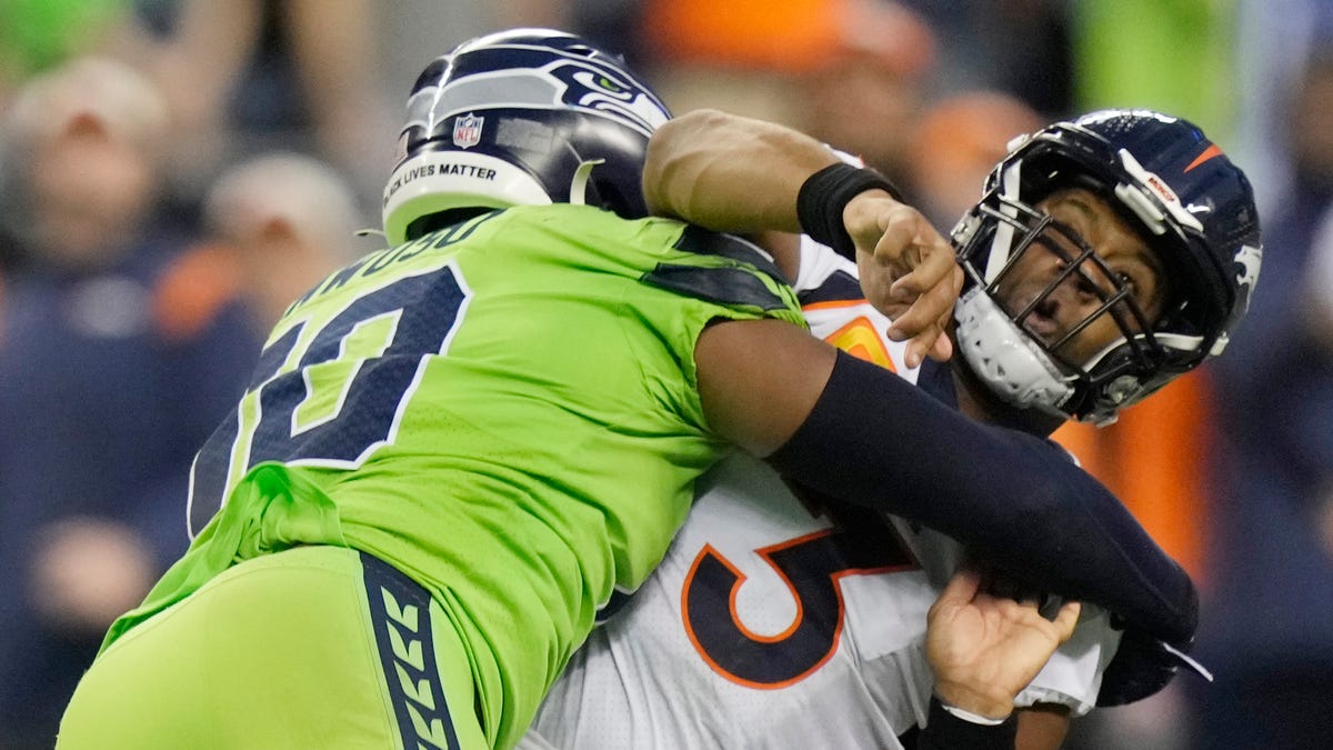 Denver Broncos quarterback Russell Wilson is hit by Seattle Seahawks linebacker Uchenna Nwosu.
