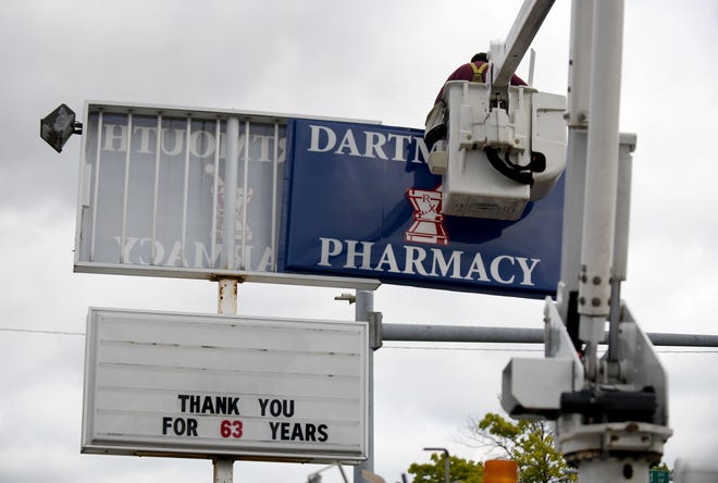 Mike Bakias du Midwest Signal Center a retiré l'enseigne de la pharmacie de Dartmouth lors de la fermeture d'un magasin de Canton pour déménager à Medicine Center Pharmacy, qui avait acheté l'entreprise.