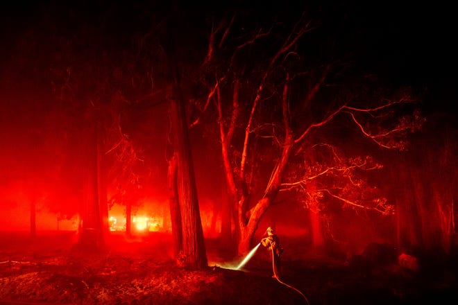 A firefighter hoses down hotspots along Foresthill Rd. as the Mosquito Fire burns in the Foresthill community of Placer County, Calif., on Tuesday, Sept. 13, 2022. (AP Photo/Noah Berger)