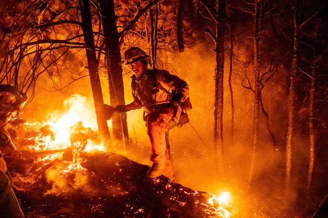 Firefighter Christian Mendoza manages a backfire, flames lit by firefighters to burn off vegetation, while battling the Mosquito Fire in Placer County, California.