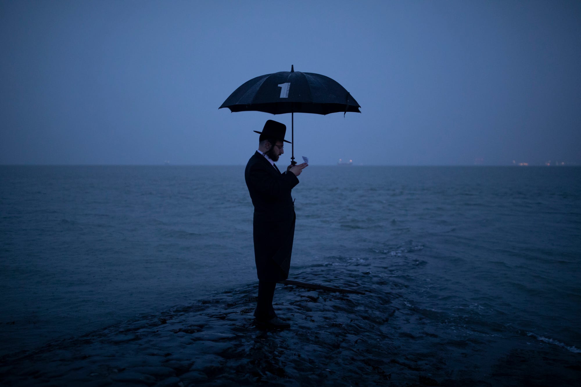 Joel Friedman and his family observe Tashlich beside the seafront at dusk on Sept. 24, 2020, in Canvey Island, England. The atonement ritual of Tashlich comes from the Hebrew word meaning