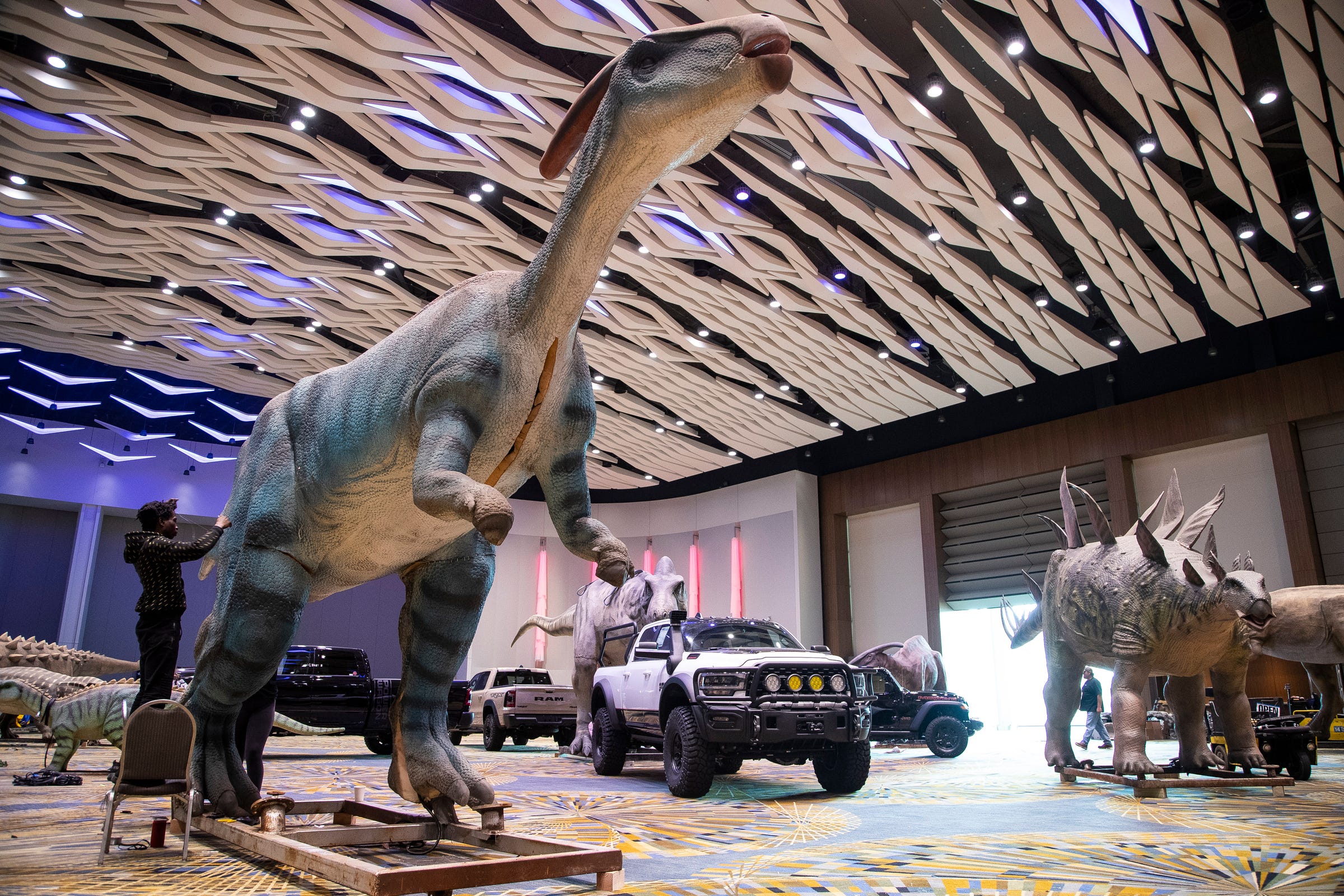 Kenny Thomas sews a dinosaur together as staff prepare for the Dinosaur and Off-Road Vehicle Encounter during the 2022 North American International Auto Show held at Huntington Place in downtown Detroit on Thursday, Sept. 15, 2022. The interactive exhibition shows off more than 80 large size dinosaurs.