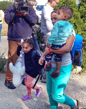 A migrant family makes their way to a bus that will take them from St. Andrews Episcopal Church in Edgartown, Mass., to a ferry in Vineyard Haven on their way to a military base on Cape Cod last Friday.