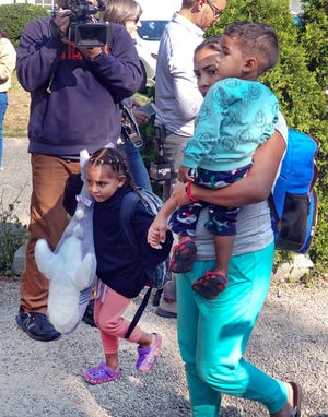 A migrant family makes their way to a bus that will take them from St. Andrews Episcopal Church in Edgartown, Mass., to a ferry in Vineyard Haven on their way to a military base on Cape Cod last Friday.