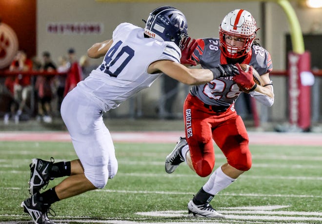 Wadsworth running back Kyle Figuray gets ready to stiff arm Hudson's Sam Scharville during the Explorers' 17-7 win over the Grizzlies on Friday night.