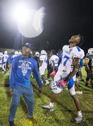 Pahokee head coach Emmanuel Hendrix celebrates victory with Pahokee defensive end Ja'Zyrain River (17) after the end of the football game between Pahokee and host Palm Beach Central on Friday, September 16, 2022, in Wellington, FL. Final score, Pahokee, 34, Palm Beach Central, 14.