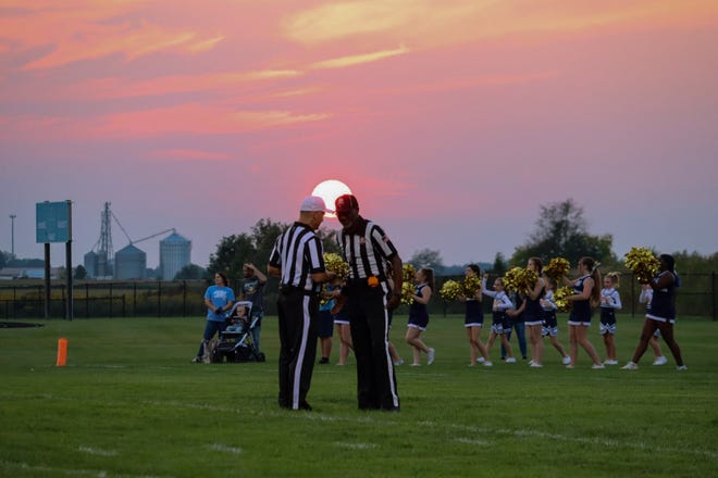 Game officials meet under a setting sun during last week's Ontario at River Valley high school football game.
