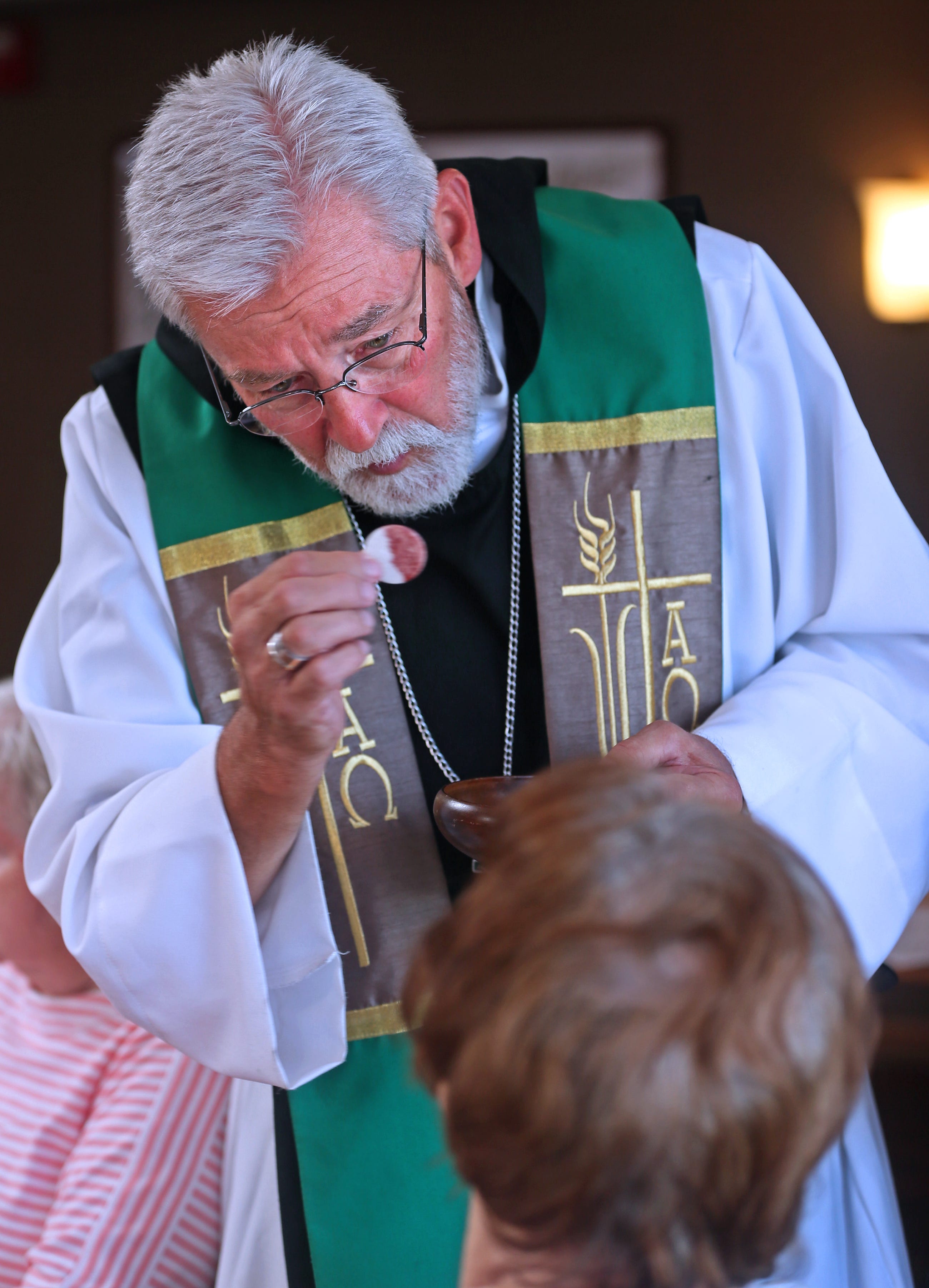 Father Steven Block gives communion during mass at Brentwood Park Home in Franklin to one of the residents. Block also has a homeless ministry called St. Martin's Mission. Block was able to help Elijah Edwards get assistance through the  Housing First program.