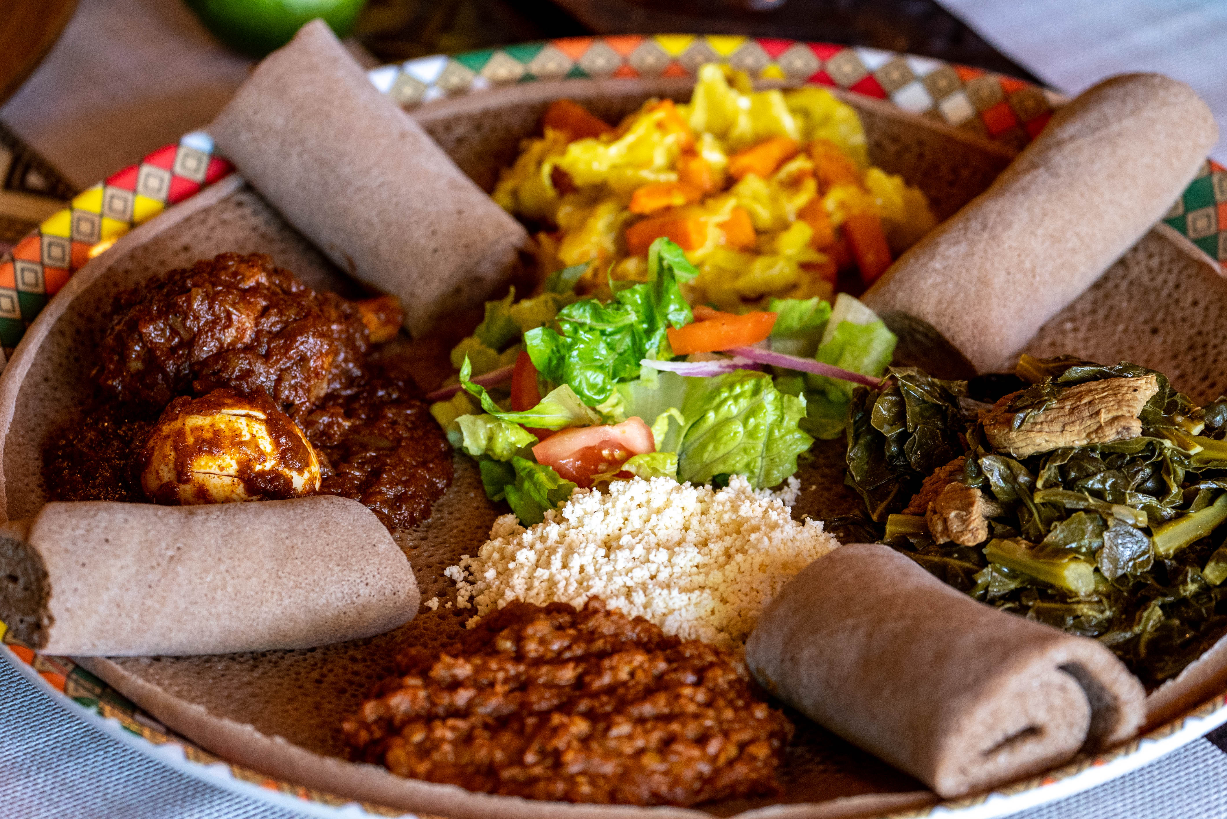 A meat and veggie sampler consisting of spicy chicken, collard greens with beef, red spicy lentils and cabbage is prepared at Authentic EthioAfrican in Phoenix on Sept. 17, 2022.