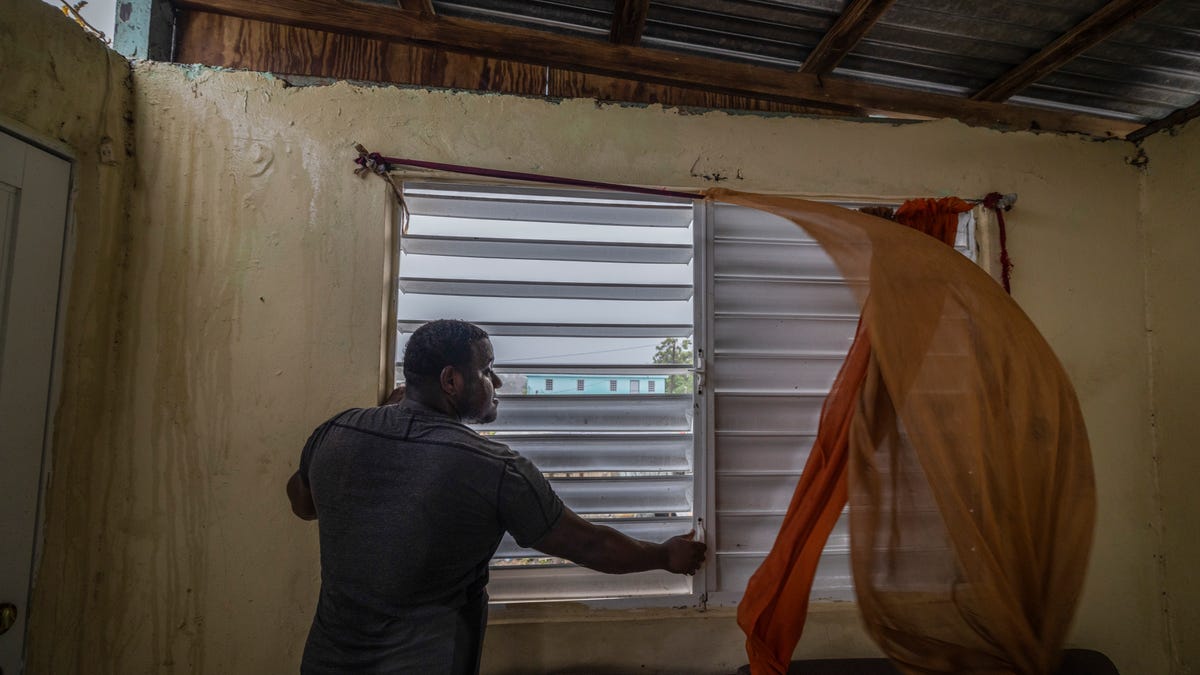 Nelson Cirino secures the windows of his home as the winds of Hurricane Fiona blow in Loiza, Puerto Rico, Sunday, Sept. 18, 2022.