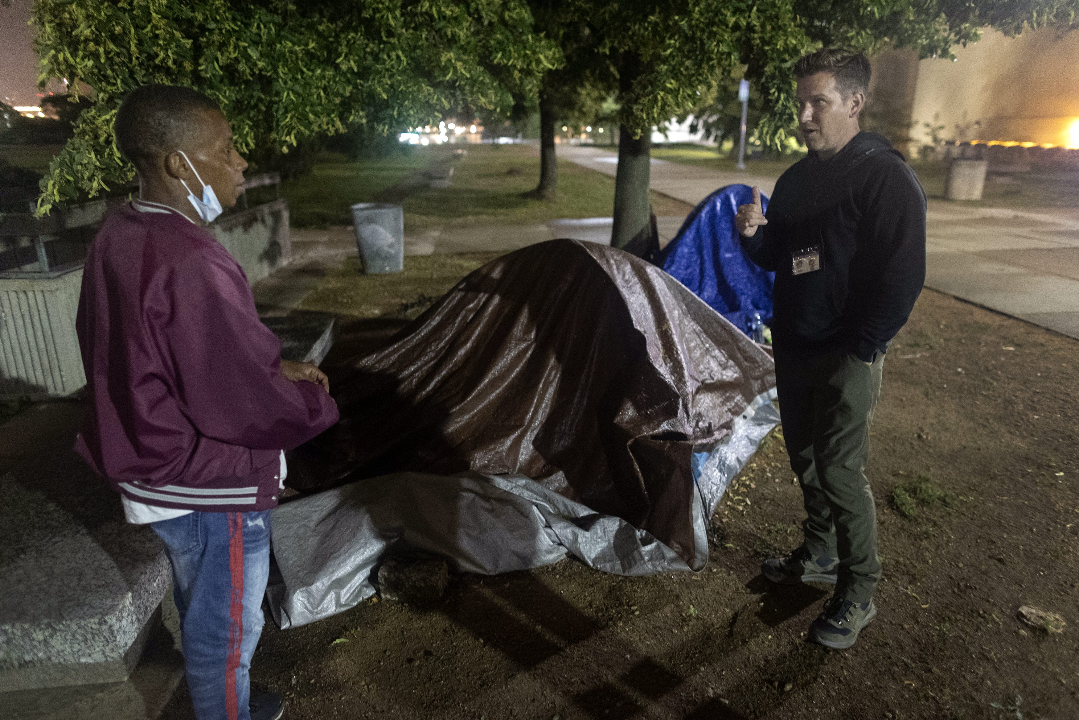 Eric Collins-Dyke, right, talks to Akeem Lawrence about getting a place to live while outside his tent in MacArthur Square Park, June 29, 2021, in downtown Milwaukee,. Collins-Dyke is , assistant administrator of supportive housing and homeless services for the Milwaukee County Housing Division.