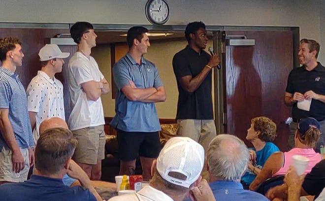 Ernest Udeh Jr. (middle) holds a microphone Monday as he speaks to the crowd at the Dale Willey Memorial Golf Tournament. Udeh was joined at the event, which was held to benefit Family Promise of Lawrence, by a number of his Kansas basketball teammates.