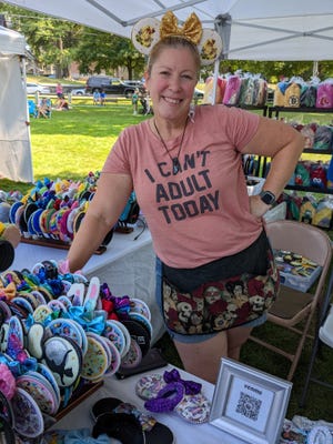 Janette Butrym wears mouse ears while posing with products at her vendor booth at Clinton’s Olde Home Day Saturday, Sept. 10.