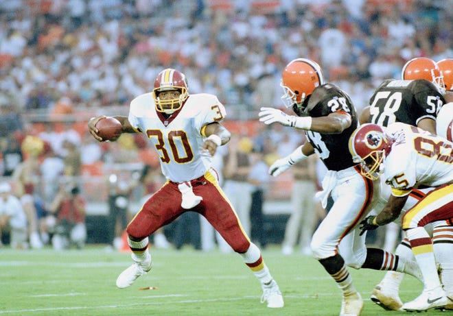 Washington Redskins running back Brian Mitchell (30) runs for long yardage past Cleveland Browns defensive back Everson Walls (28) during the first quarter in Washington, Aug. 9, 1993. Redskins' Tim McGee (85) comes in to help from right.