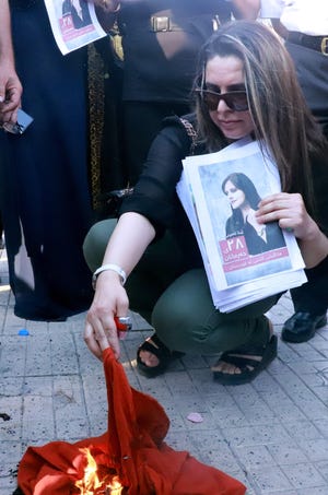 Iranian Kurds set a headscarf on fire during a march in a park in the Iraqi Kurdish city of Sulaimaniya on September 19, 2022, against the killing of Mahsa Amini.