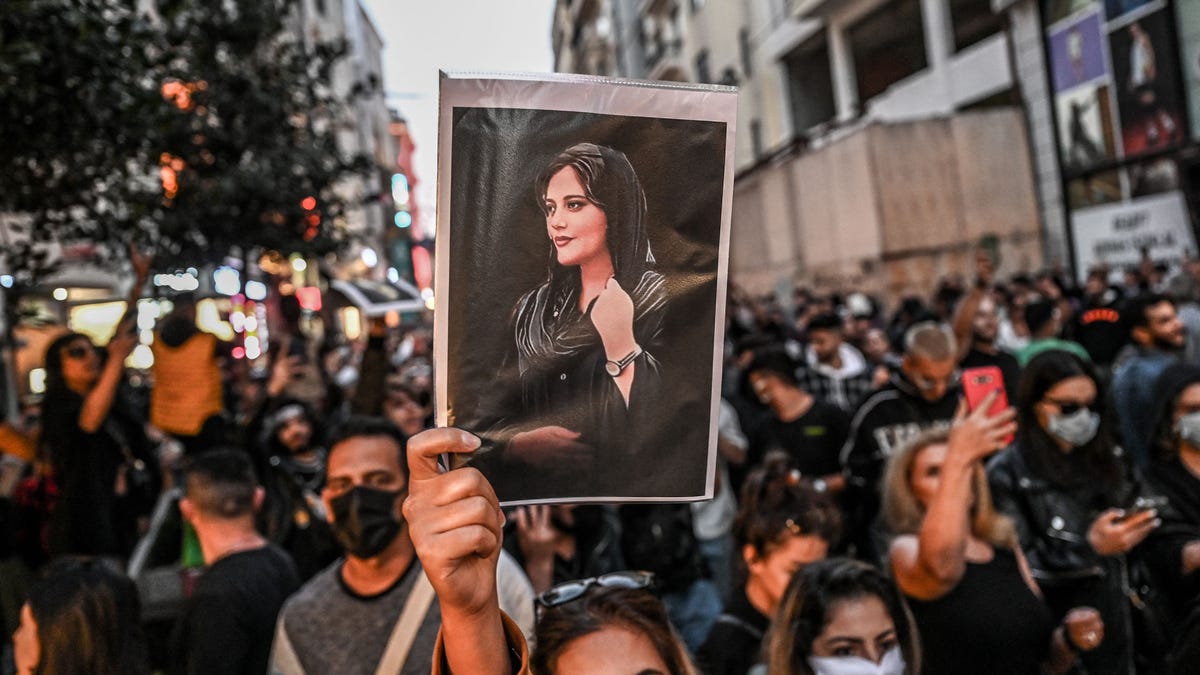 A protester holds a portrait of Mahsa Amini  during a demonstration in support of Amini, a young Iranian woman who died after being arrested in Tehran by the Islamic Republic's morality police, on Istiklal avenue in Istanbul on September 20, 2022. - Amini, 22, was on a visit with her family to the Iranian capital when she was detained on September 13 by the police unit responsible for enforcing Iran's strict dress code for women, including the   wearing of the headscarf in public. She was declared dead on September 16 by state television after having spent three days in a coma. (Photo by Ozan KOSE / AFP) (Photo by OZAN KOSE/AFP via Getty Images)