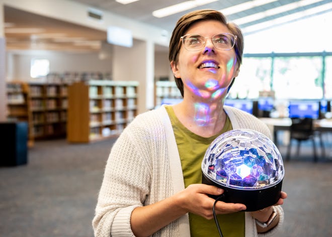 Emily Weber-Wood, a marketing and fundraising specialist for the Bucks County Free Library, tests out a new disco light, on Wednesday, August 31, 2022. The light is among the many party supplies available for loan as a part of the library's non-book collection.