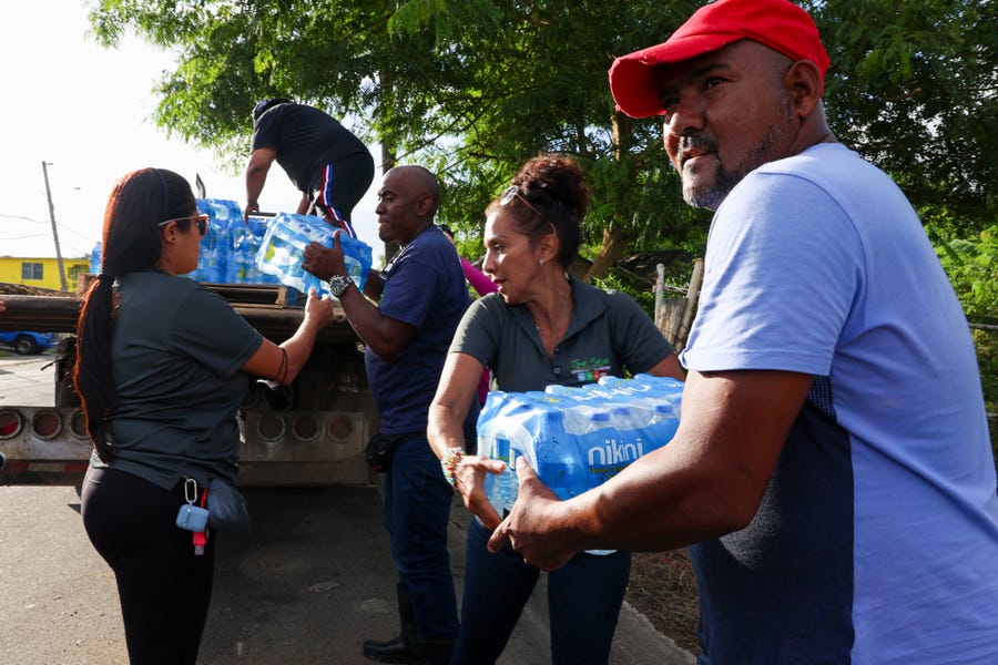A man collects donated water bottles for drinking after Hurricane Fiona damaged water supplies in Toa Baja, Puerto Rico, Tuesday, Sept. 20, 2022.
